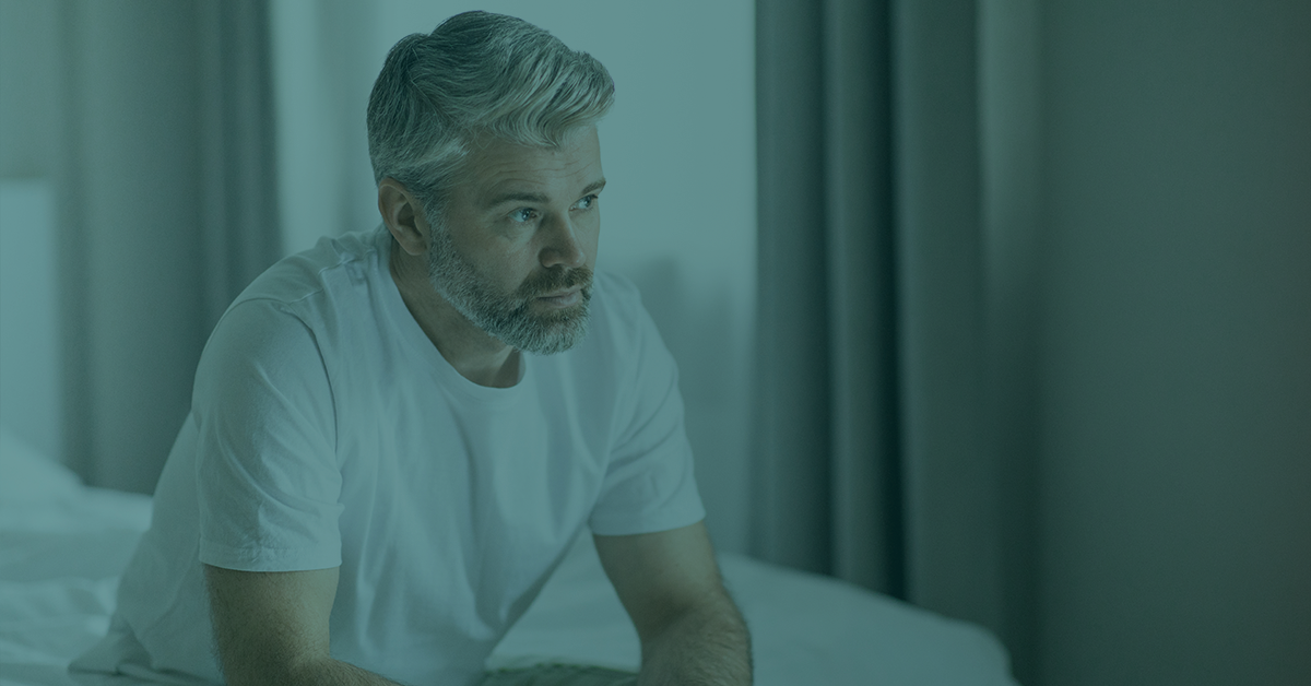 Middle aged man sitting on edge of bed