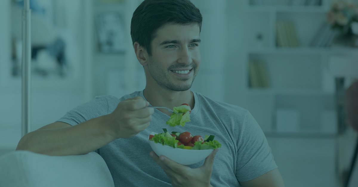 Smiling man eating salad